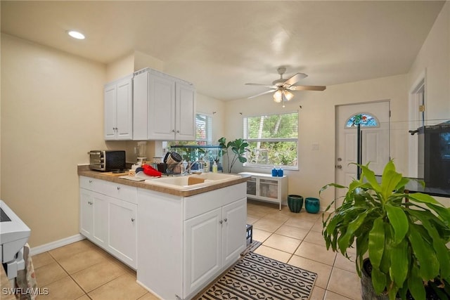 kitchen featuring ceiling fan, light tile patterned flooring, white cabinetry, and sink