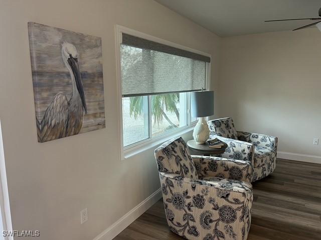 living area with ceiling fan and dark hardwood / wood-style flooring