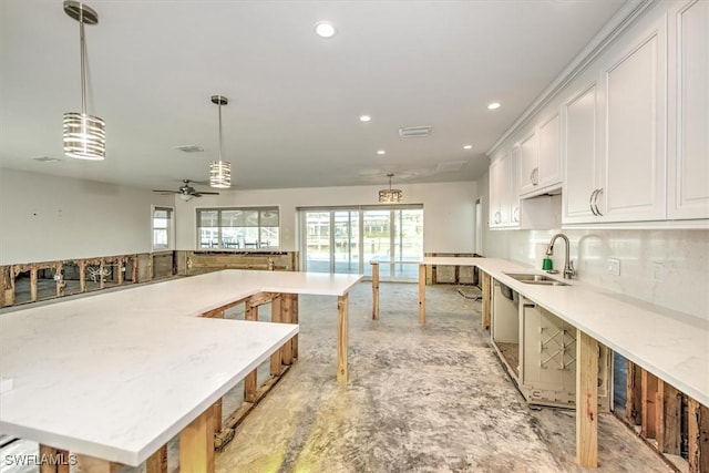 kitchen with tasteful backsplash, ceiling fan, sink, pendant lighting, and white cabinetry