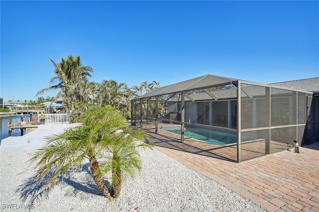 view of swimming pool with glass enclosure, a water view, and a patio