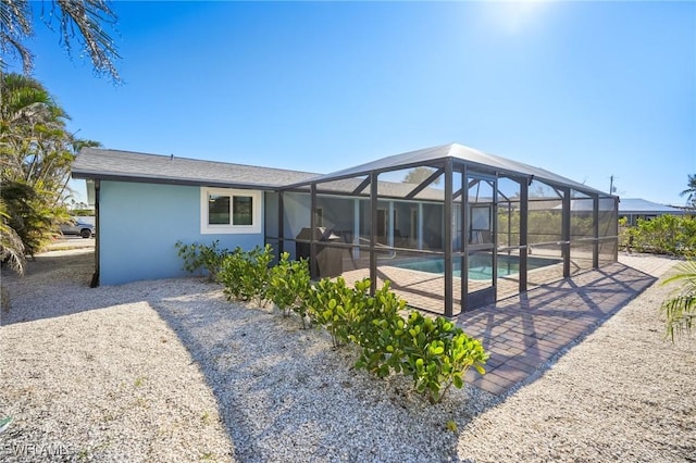 rear view of property featuring glass enclosure and a patio