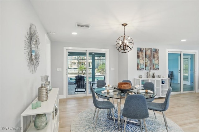 dining room with light hardwood / wood-style floors, french doors, and an inviting chandelier