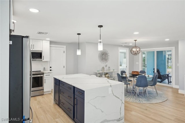 kitchen featuring light hardwood / wood-style floors, white cabinets, hanging light fixtures, and appliances with stainless steel finishes