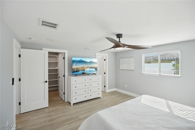 bedroom with ceiling fan, a walk in closet, light hardwood / wood-style flooring, and a closet