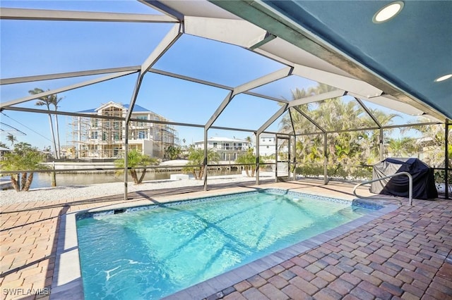 view of swimming pool with a patio area, a lanai, and a water view