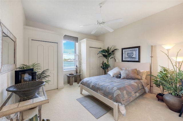 bedroom with light carpet, two closets, and ceiling fan