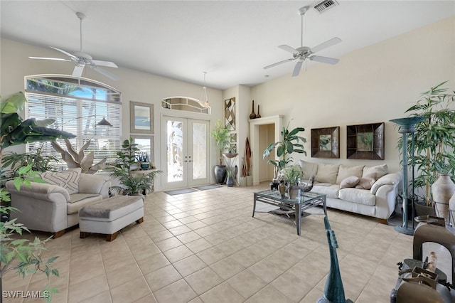 living room featuring french doors, ceiling fan, light tile patterned flooring, and a towering ceiling