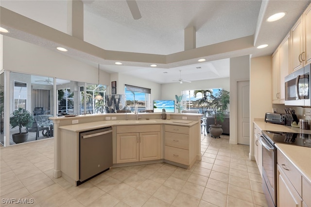 kitchen featuring light tile patterned flooring, appliances with stainless steel finishes, sink, ceiling fan, and a raised ceiling