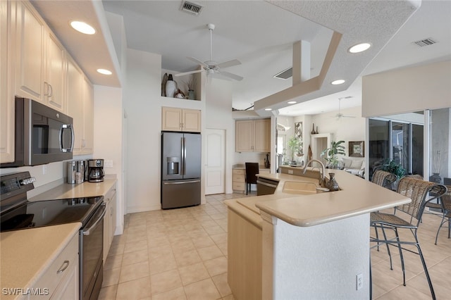 kitchen with appliances with stainless steel finishes, sink, a breakfast bar area, a kitchen island with sink, and ceiling fan