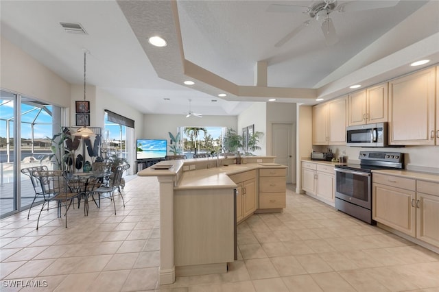 kitchen featuring vaulted ceiling, light tile patterned flooring, a center island, ceiling fan, and stainless steel appliances