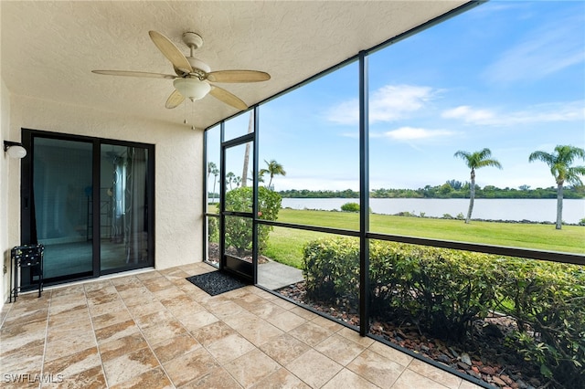 unfurnished sunroom featuring a water view, ceiling fan, and plenty of natural light