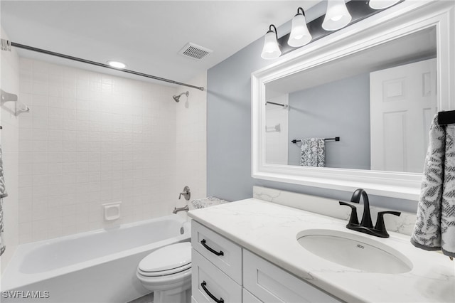 full bathroom featuring tiled shower / bath, vanity, and toilet