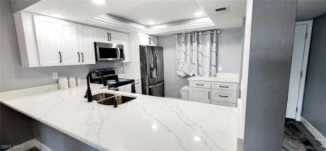 kitchen with stainless steel appliances, a raised ceiling, sink, and white cabinets