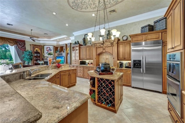 kitchen with stainless steel appliances, a tray ceiling, a spacious island, sink, and hanging light fixtures