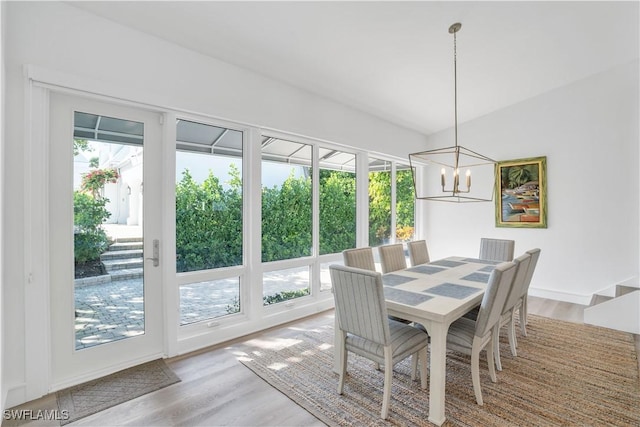 dining area featuring an inviting chandelier, a healthy amount of sunlight, and hardwood / wood-style flooring