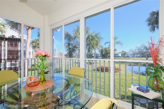 sunroom / solarium featuring a water view, a healthy amount of sunlight, and vaulted ceiling