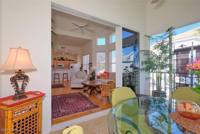 living room with ceiling fan, a towering ceiling, and light tile patterned floors