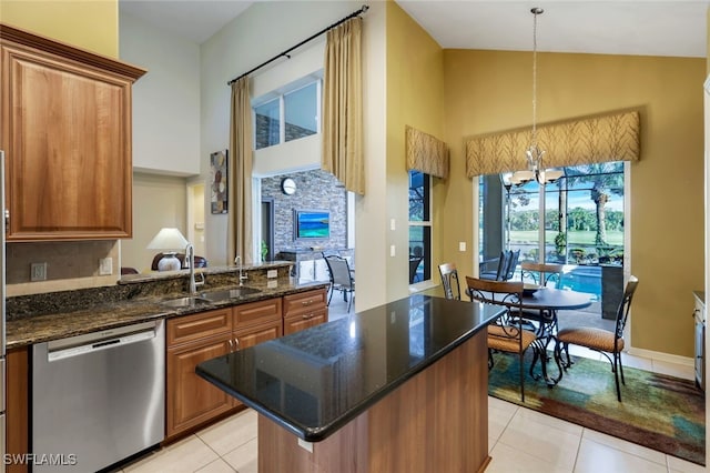 kitchen with sink, light tile patterned floors, dark stone countertops, dishwasher, and pendant lighting