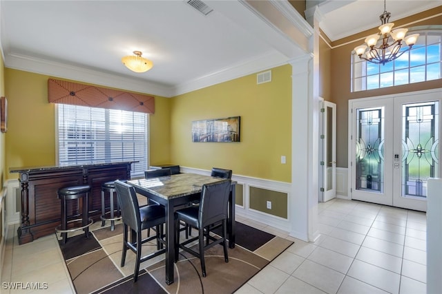 tiled dining room with crown molding, french doors, and ornate columns