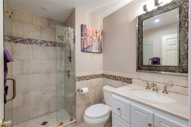 bathroom with vanity, a shower with shower door, tile walls, and toilet