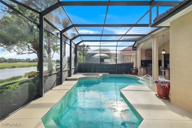 view of swimming pool featuring an outdoor kitchen, a patio area, a water view, glass enclosure, and an in ground hot tub