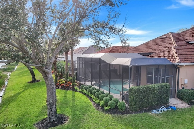 exterior space with glass enclosure and a lawn