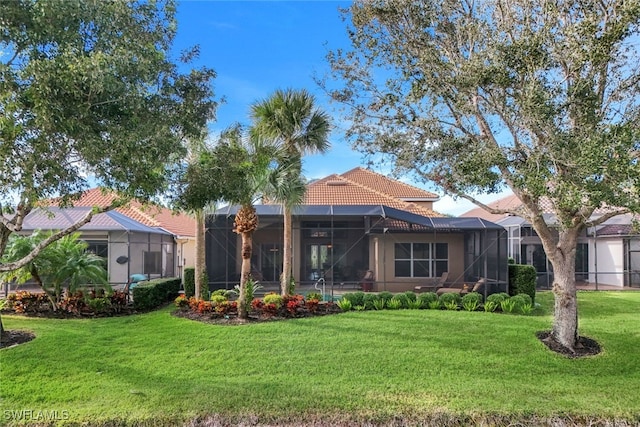 rear view of house with a yard and a lanai