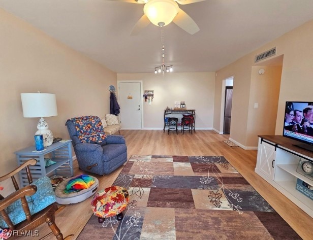 living room with ceiling fan with notable chandelier and light hardwood / wood-style flooring