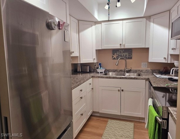 kitchen with white cabinets, sink, and stainless steel refrigerator