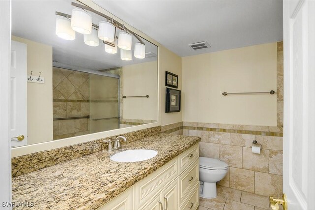 bathroom with toilet, tile walls, tile patterned floors, walk in shower, and vanity