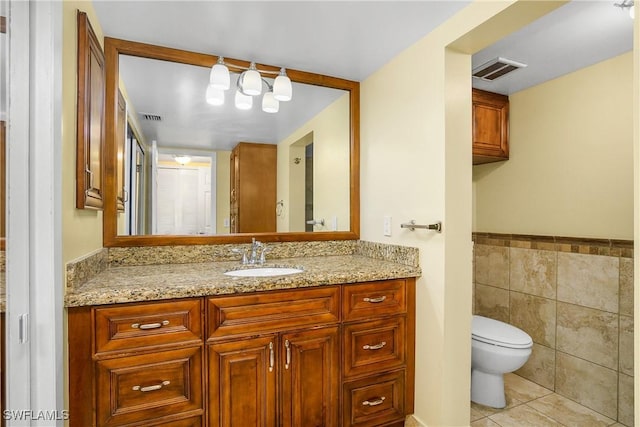 bathroom featuring toilet, tile patterned flooring, tile walls, and vanity