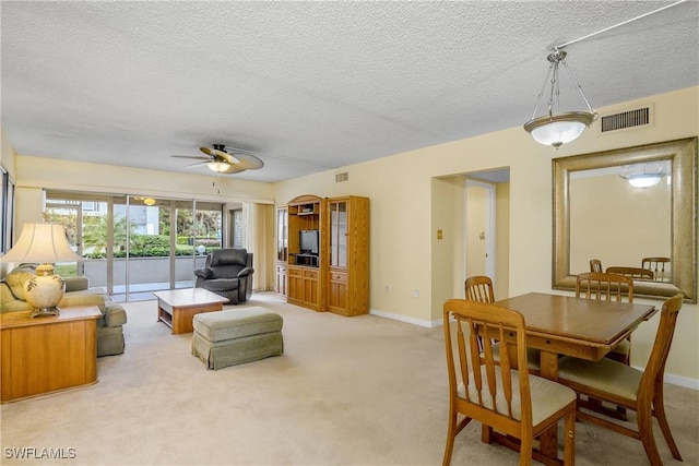 living room with ceiling fan, a textured ceiling, and light carpet