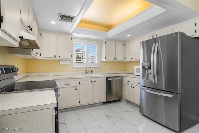 kitchen featuring a raised ceiling, cream cabinetry, appliances with stainless steel finishes, and sink