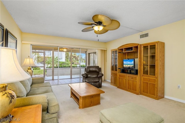 living room with ceiling fan, a textured ceiling, and light carpet