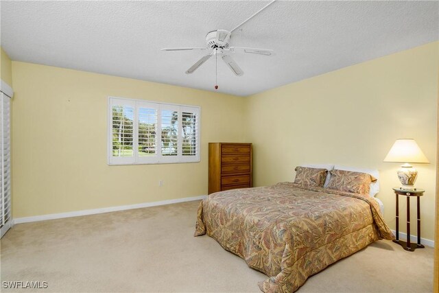 bedroom with light carpet, ceiling fan, and a textured ceiling