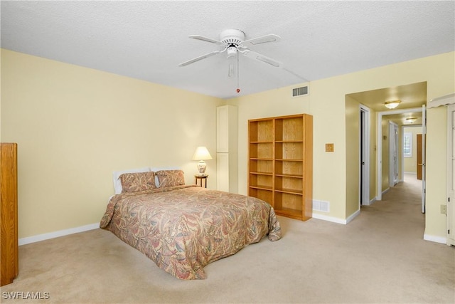 bedroom with ceiling fan, light colored carpet, and a textured ceiling