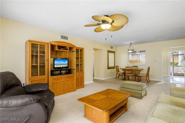 carpeted living room featuring ceiling fan and a textured ceiling