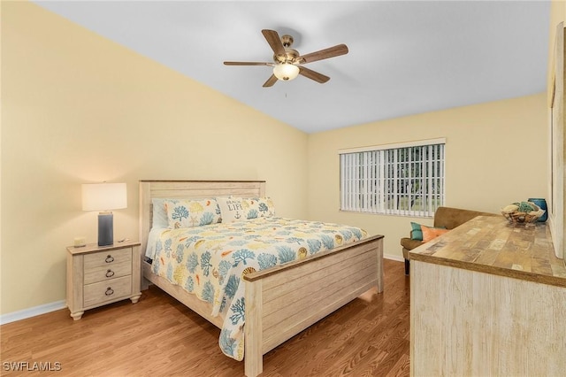 bedroom with wood finished floors, baseboards, lofted ceiling, and a ceiling fan