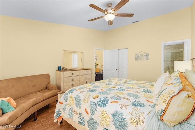 bedroom featuring wood finished floors, ensuite bath, and a ceiling fan