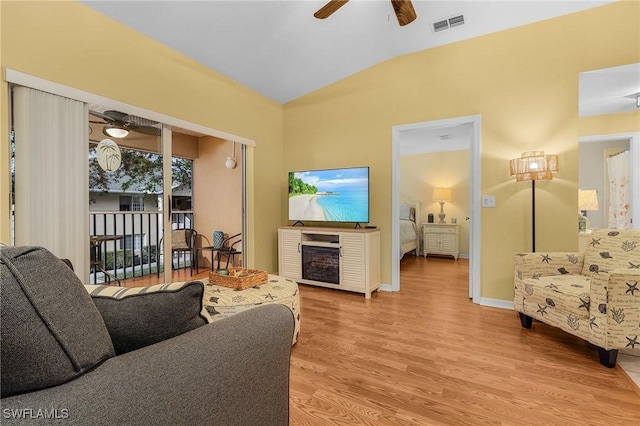 living area featuring a fireplace, visible vents, light wood-style floors, vaulted ceiling, and a ceiling fan