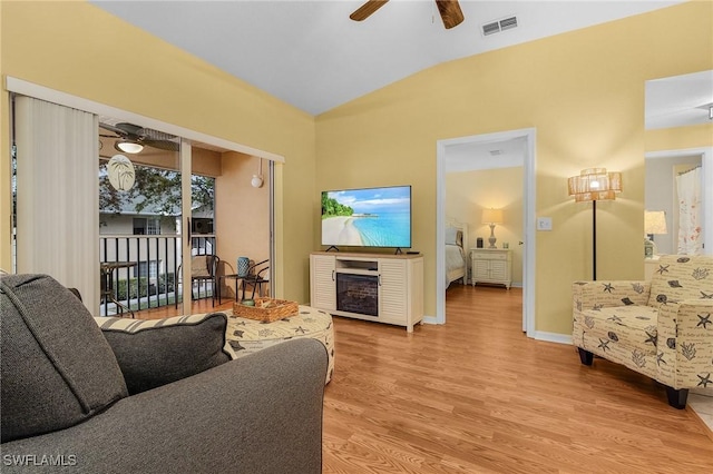 living area featuring ceiling fan, vaulted ceiling, wood finished floors, and a fireplace