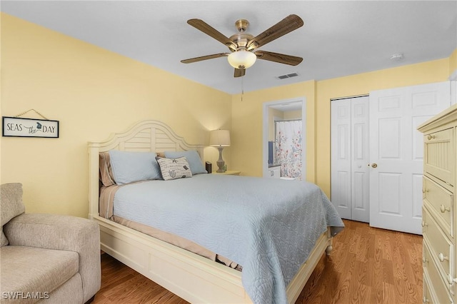 bedroom featuring light wood finished floors, ceiling fan, visible vents, and a closet