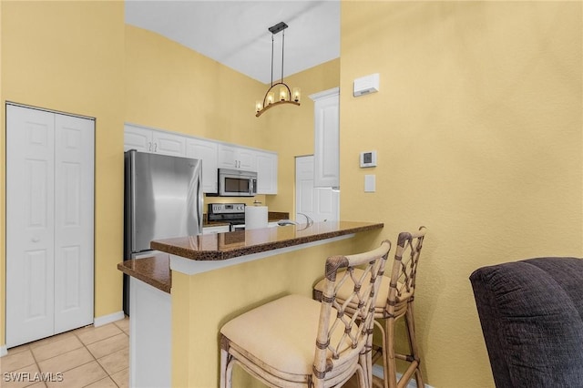 kitchen with stainless steel appliances, white cabinets, a peninsula, and a breakfast bar area