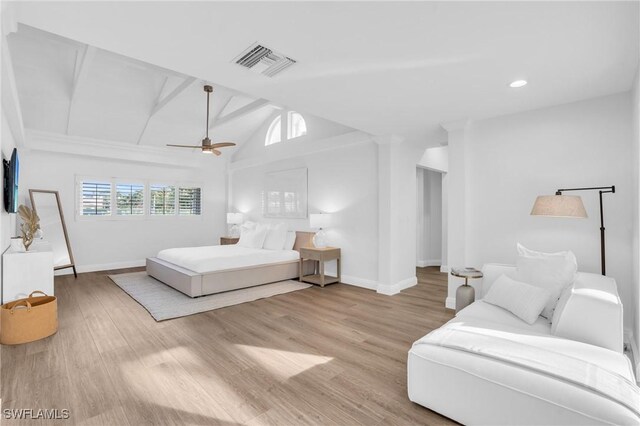 bedroom featuring ceiling fan, light hardwood / wood-style floors, and vaulted ceiling with beams