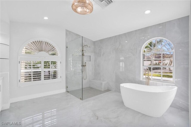 bathroom with tile walls and independent shower and bath