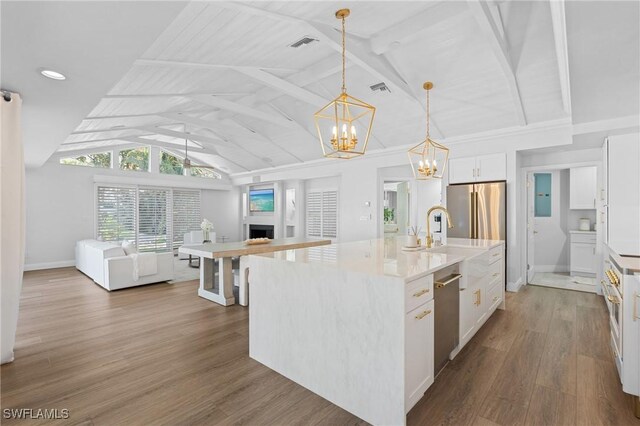 kitchen with appliances with stainless steel finishes, pendant lighting, white cabinetry, dark wood-type flooring, and a center island with sink