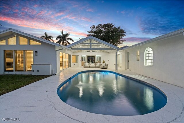 pool at dusk with an outdoor living space and a patio area