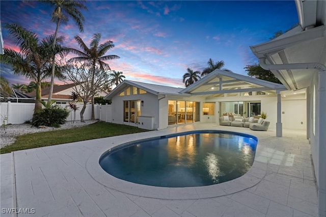 pool at dusk with a patio area and outdoor lounge area