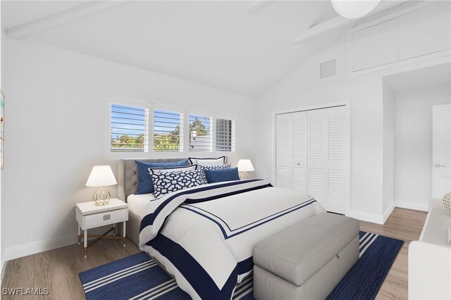 bedroom featuring hardwood / wood-style flooring, beamed ceiling, high vaulted ceiling, and a closet