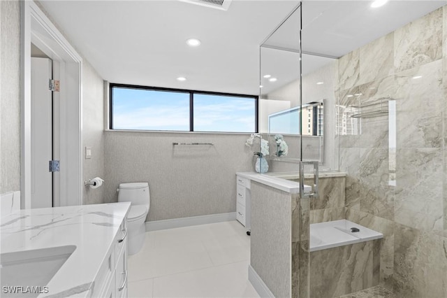 bathroom with tiled shower, vanity, toilet, and tile patterned flooring